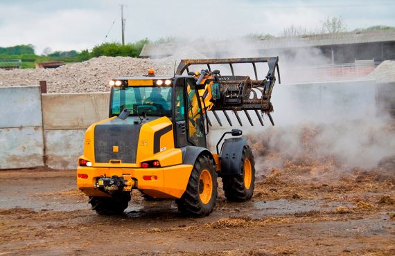 Gelber Radlader beim Mistschieben.