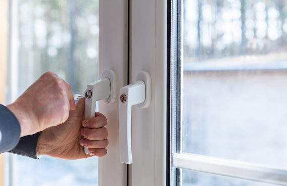 Zwei Fenstergriffe, die durch Schlösser abschließbar sind. Das linke Schloss wird gerade abgeschlossen.